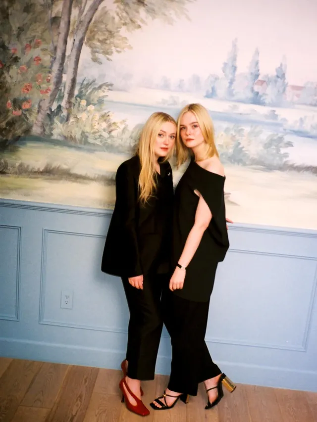 Elle Fanning posing in a black outfit beside another woman.