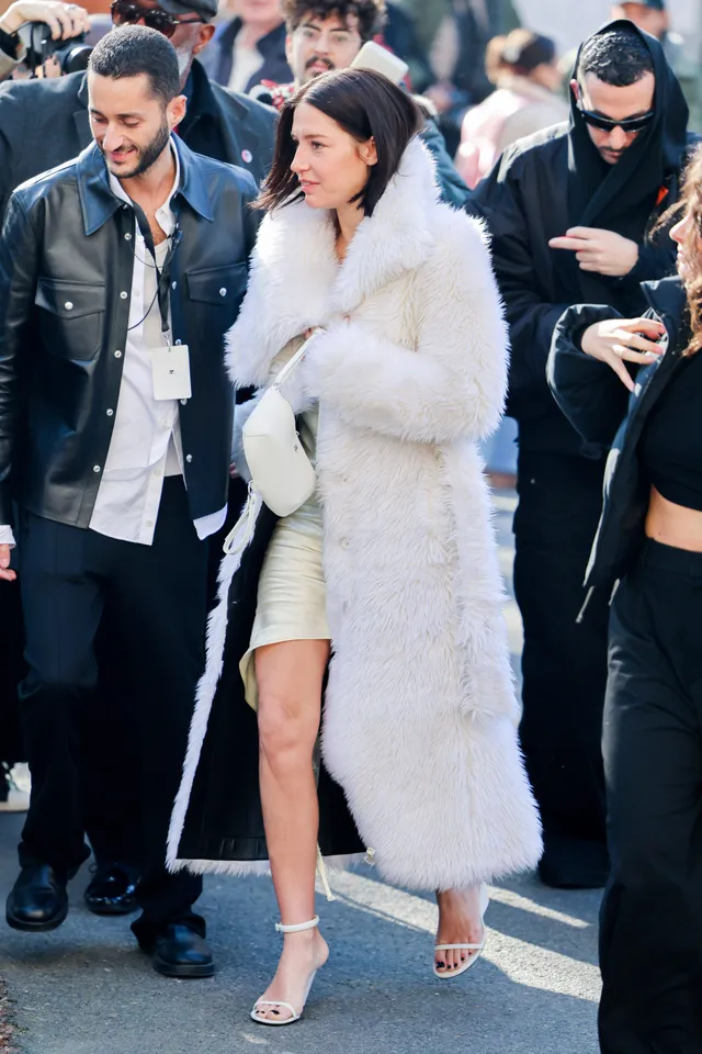 Adèle Exarchopoulos walking beside guests in a white coat.