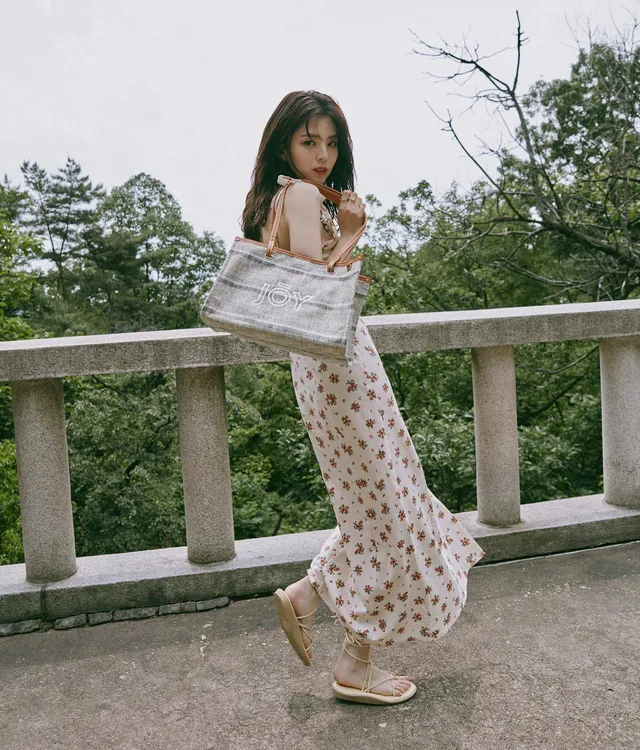 Han So-hee posing outdoors in a floral dress and sandals.