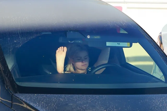 Ariel Winter sitting inside a parked car with bare feet raised.