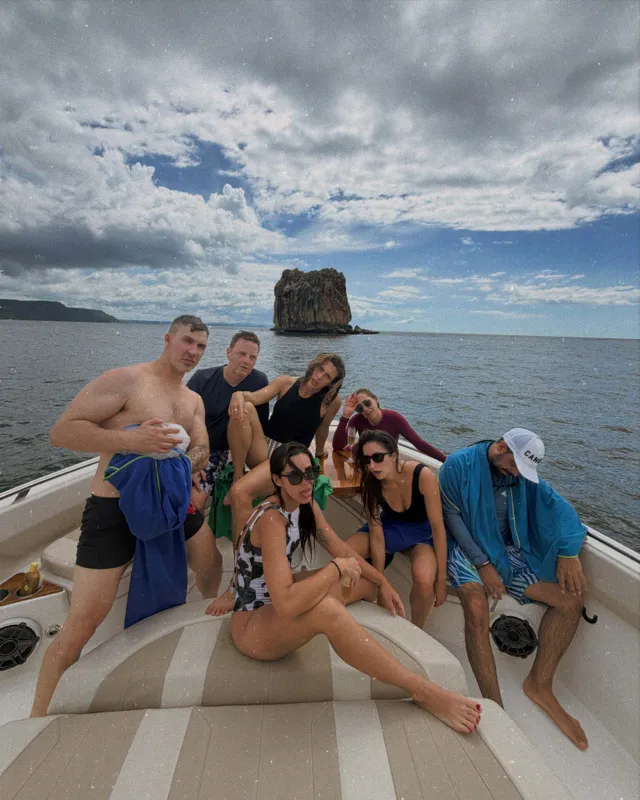 María Gabriela de Faría sitting barefoot on a boat with friends.