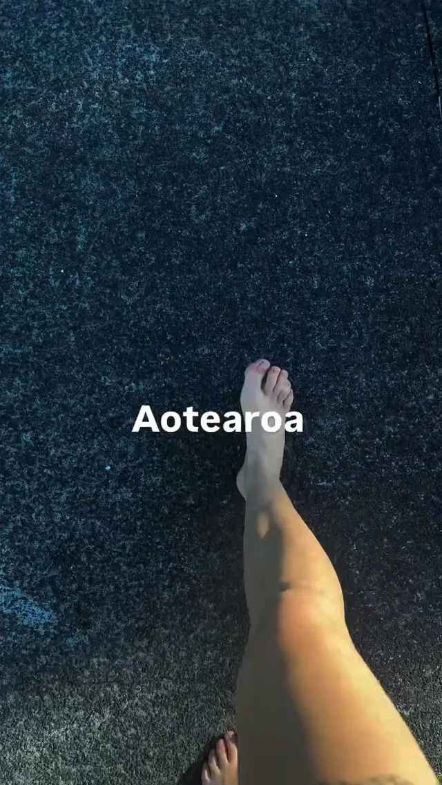 Tove Lo walking barefoot across dark carpet.