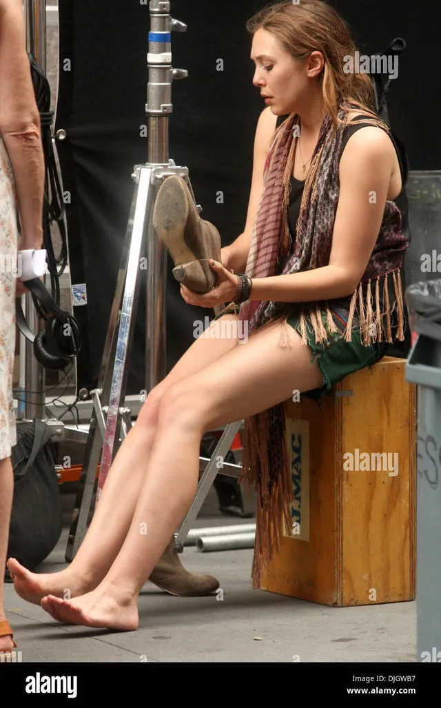 Elizabeth Olsen sitting barefoot beside filming equipment.