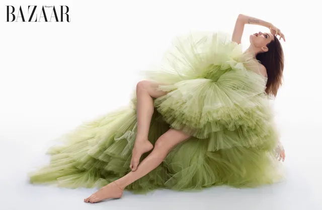 Angelina Jolie reclining in a flowing green dress for a fashion portrait.
