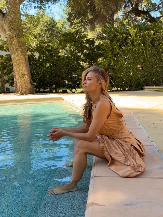 Eva Mendes sitting at the edge of a swimming pool.