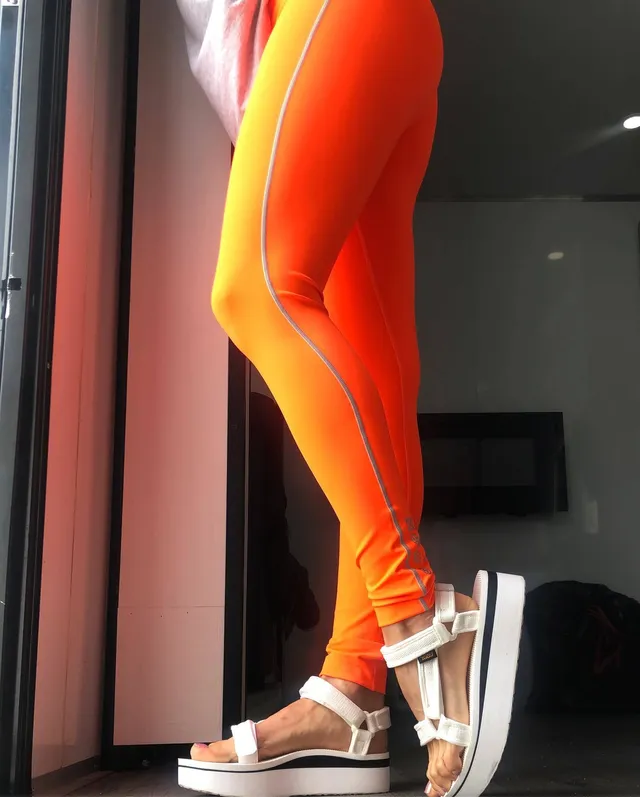Debby Ryan wearing orange trousers and white platform sandals.