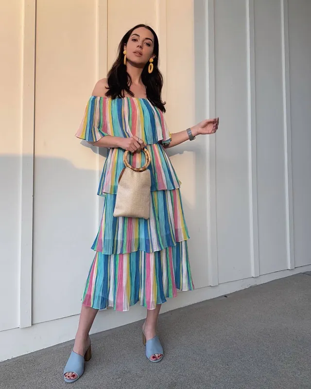 Adelaide Kane posing in a striped dress and blue open-toe shoes.