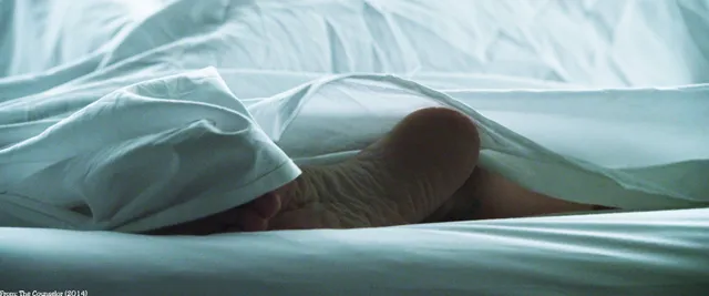 Penélope Cruz showing a bare sole beneath pale bed sheets.
