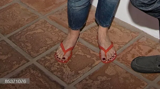 Gwen Stefani wearing red flip-flops on a tiled floor.