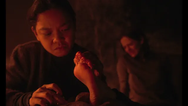 Eva Green a dimly lit screen scene holding a bare foot.
