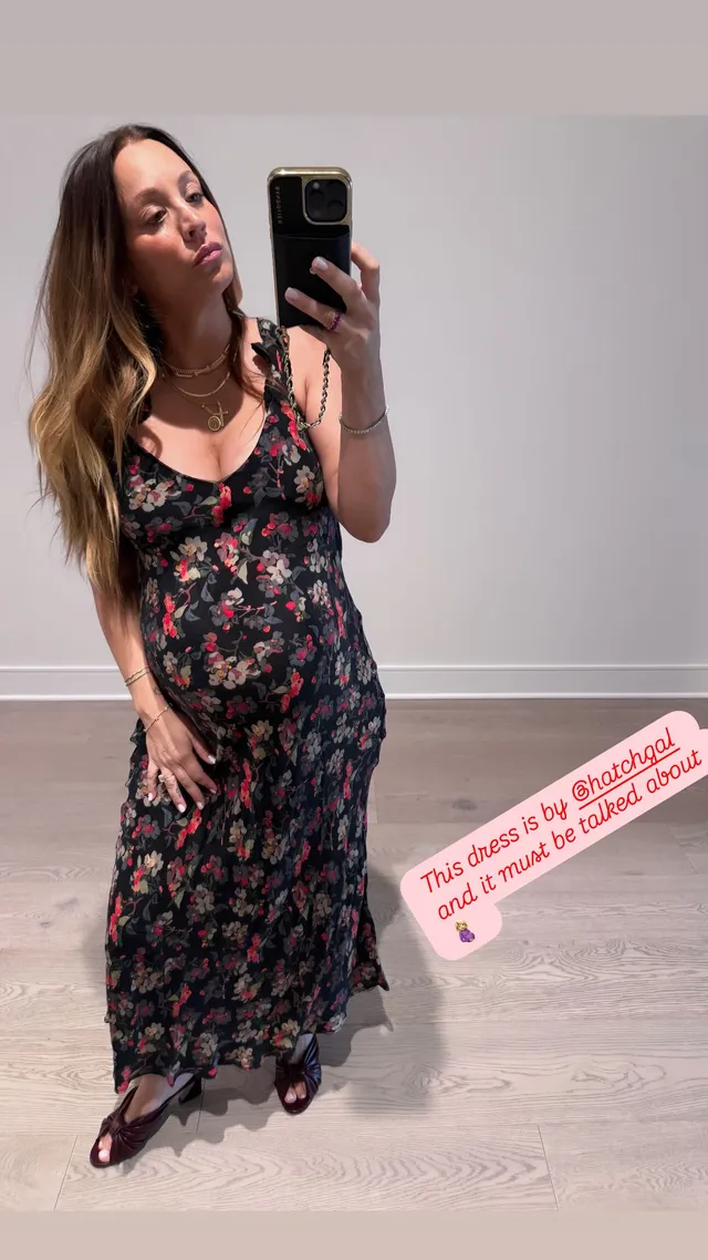 Kaley Cuoco posing for a mirror photograph in a floral maxi dress and black sandals.