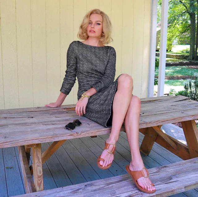 Kate Bosworth sitting on a picnic table in flat pink sandals.