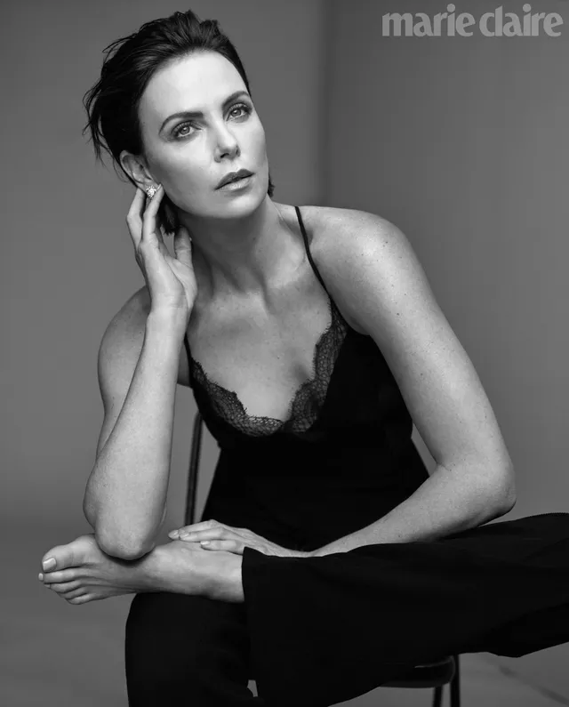 Charlize Theron a monochrome portrait seated against a grey backdrop.