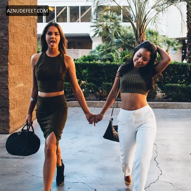 Cierra Ramirez in a dark crop top and trousers walking beside a friend outdoors.