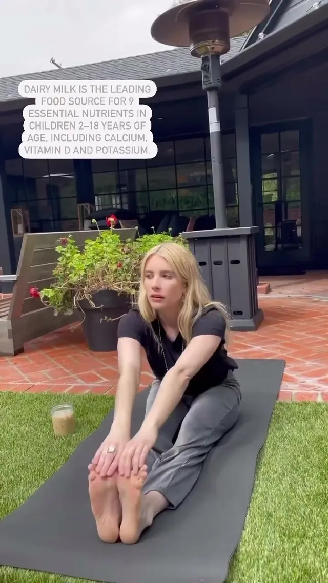 Emma Roberts stretching on an outdoor mat with bare soles visible.