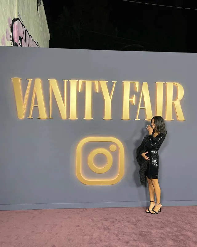 Greta Onieogou posing before an event wall in a black dress and heels.