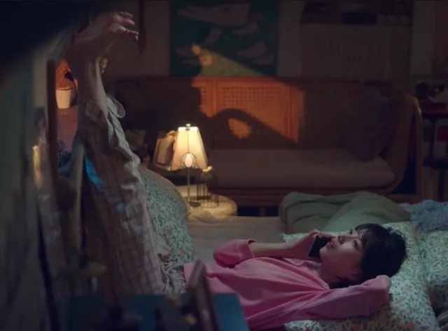 Bae Suzy raising her bare feet beside a bed in a scene.