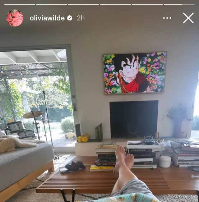 Olivia Wilde resting her bare feet on a coffee table.
