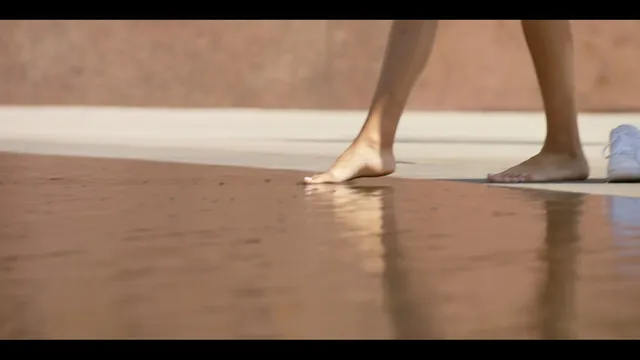 Samantha Logan shown in a close-up walking barefoot indoors.