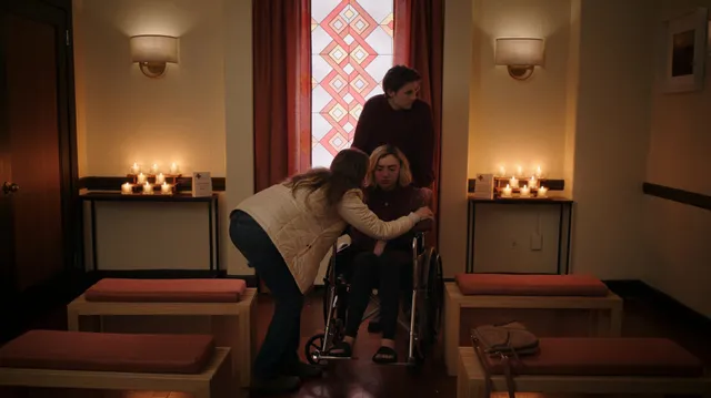 Peyton List standing beside other people in an indoor television scene.