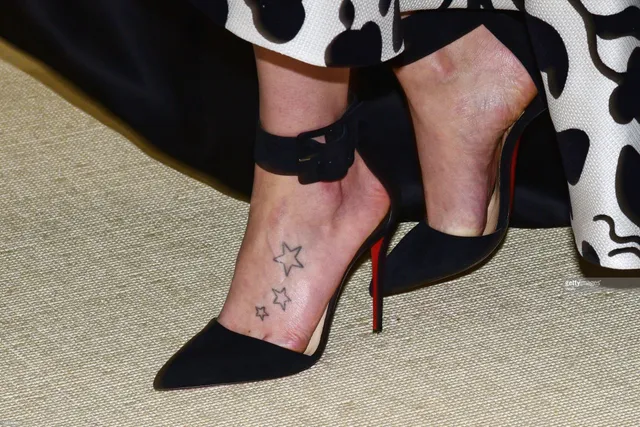 Daisy Ridley wearing pointed black ankle strap pumps.