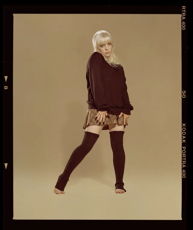 Billie Eilish a burgundy outfit with footless tights in a studio.