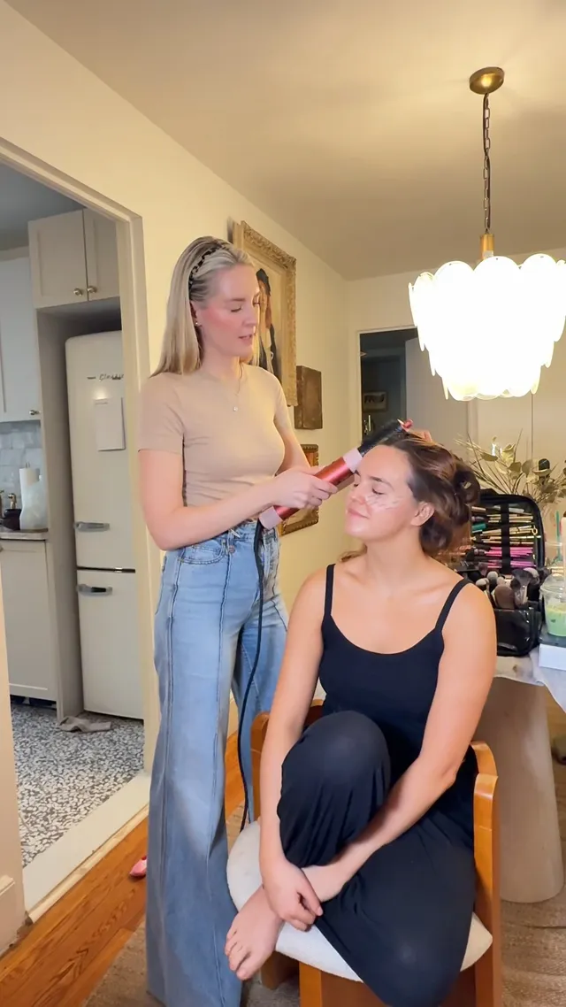 Bailee Madison sitting barefoot beside a makeup artist.