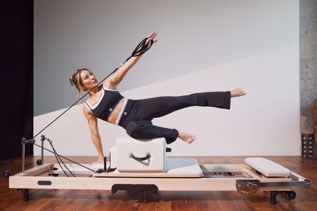 Hilary Duff exercising barefoot on a Pilates reformer.