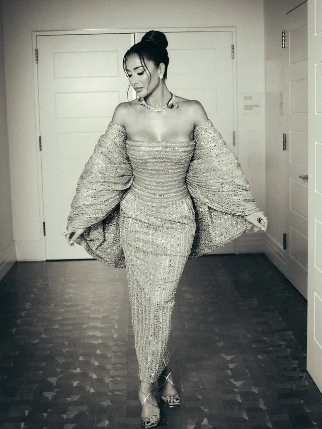 Nicole Scherzinger posing indoors in an embellished gown and metallic heels.