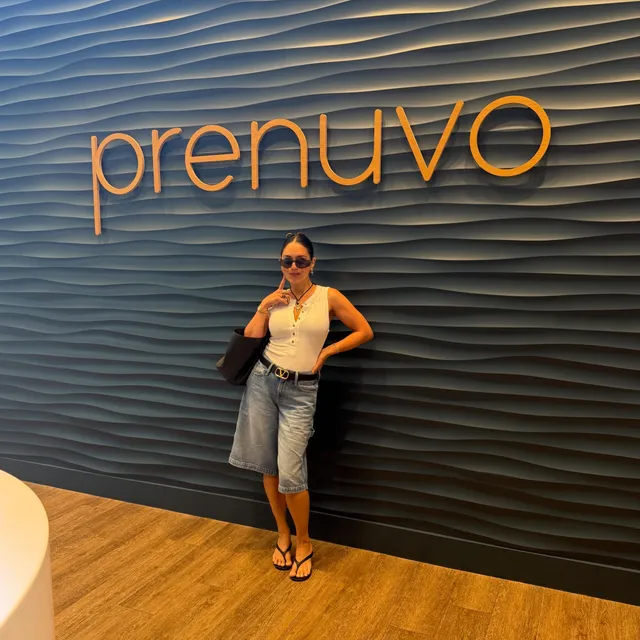 Vanessa Hudgens standing in denim shorts and black heels by an event backdrop.