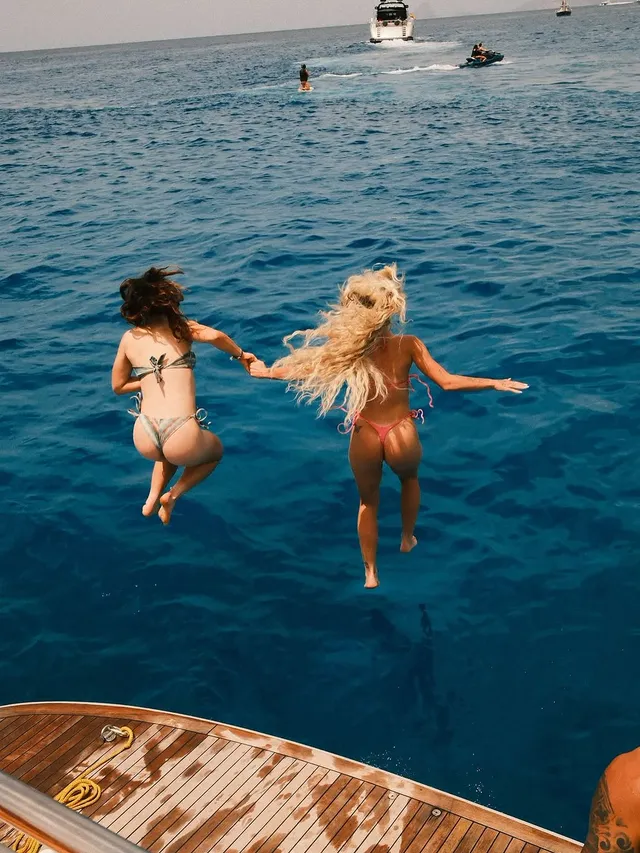 Alisha Lehmann jumping barefoot into the sea with a companion.