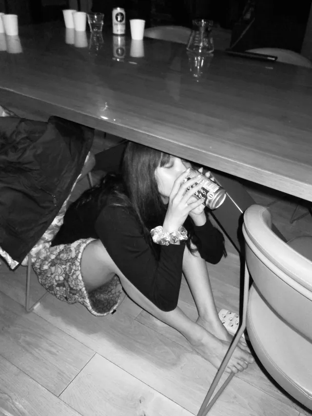 Lisa (Lalisa Manobal) kneeling barefoot beside a table during a monochrome photograph.