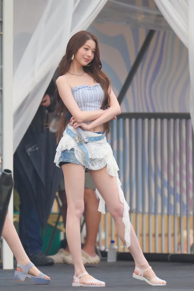 Jang Wonyoung walking outdoors in shorts and flat sandals.