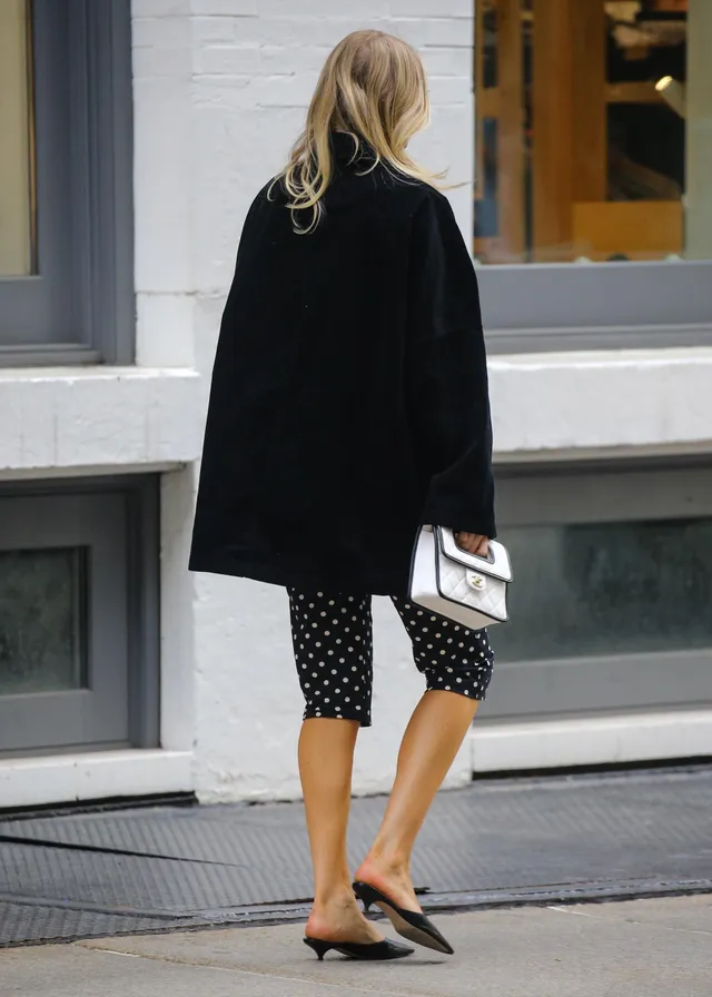 Elsa Hosk walking in flat sandals and patterned cropped trousers.
