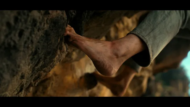 Charlize Theron a screen detail of a bare foot on a rock face.