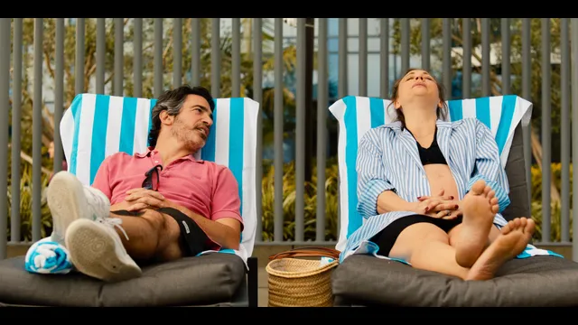 Kaley Cuoco reclining in a striped deckchair with her bare soles visible.