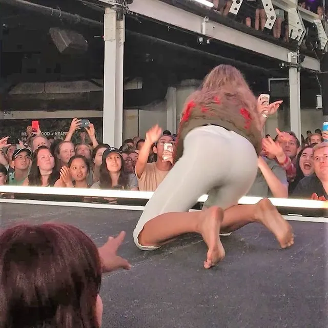 Tove Lo kneeling barefoot near fans at the front of a stage.