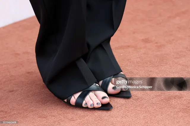 Grace Van Patten wearing black heeled sandals beneath dark trousers.