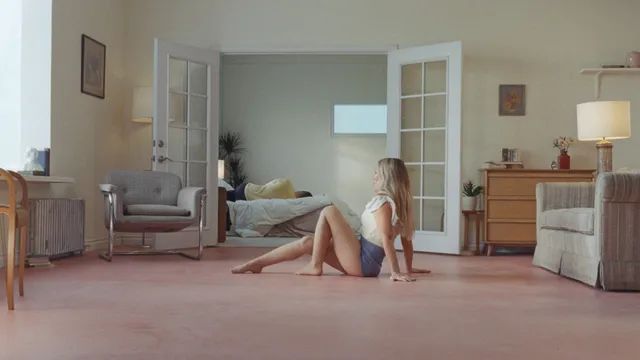 Hilary Duff sitting barefoot on the floor in a pale room.
