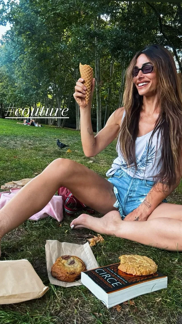 Sarah Shahi sitting on grass during a picnic.
