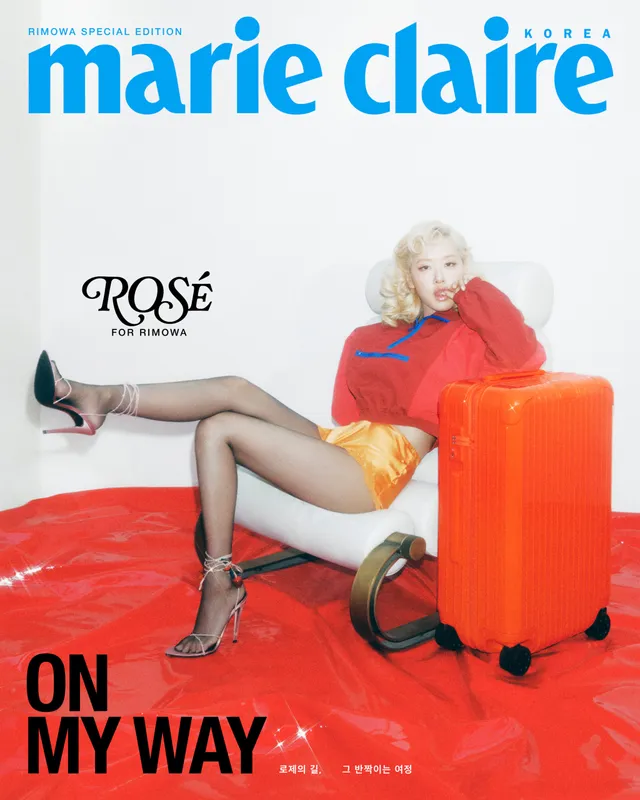 Rosé posing on a magazine cover in a red top, shorts and patterned high heels beside an orange suitcase.