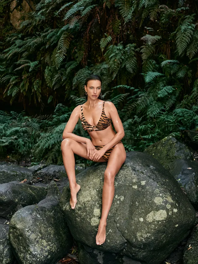 Irina Shayk a seated portrait on a large rock.