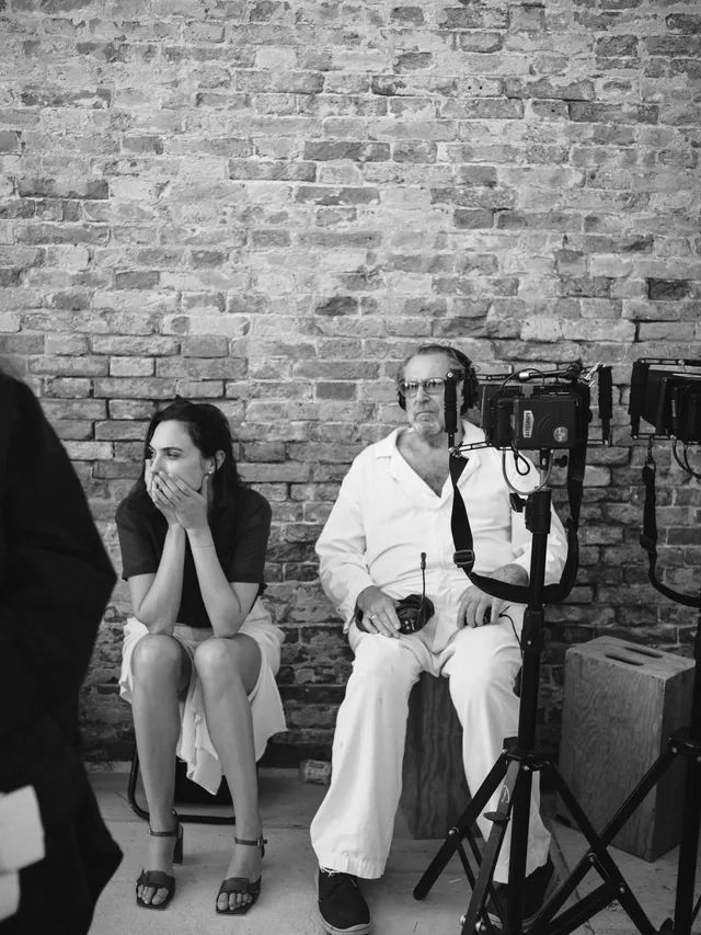 Gal Gadot sitting in an interview wearing black heeled sandals.