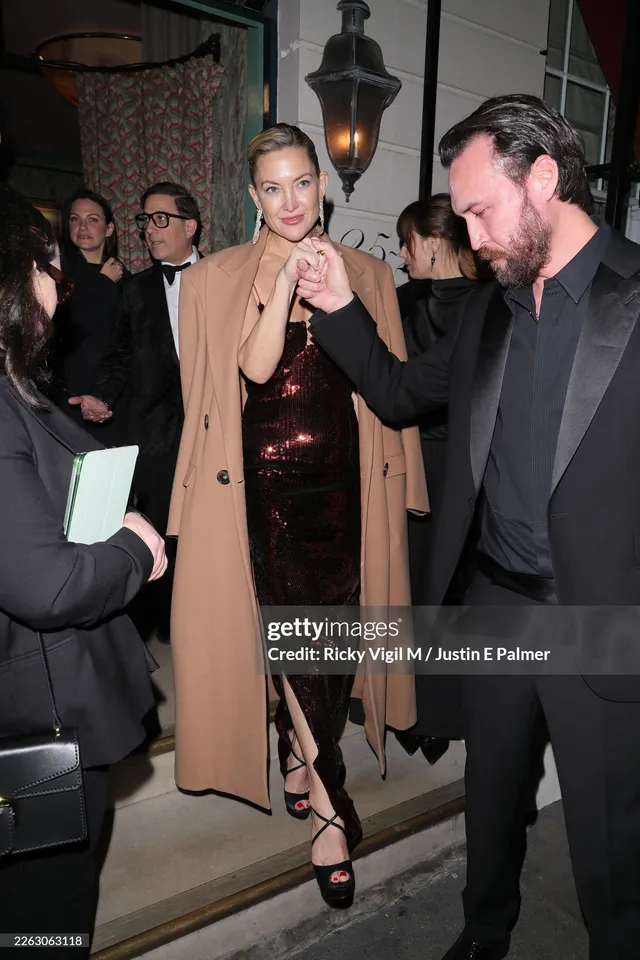 Kate Hudson walking among guests in black strappy sandals.