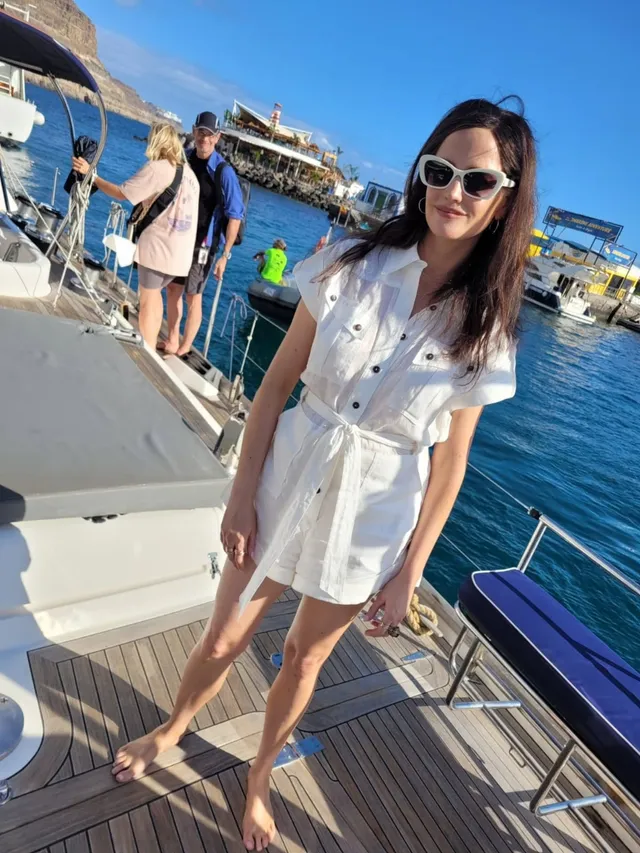 Eva Green standing on a boat deck in a white outfit.