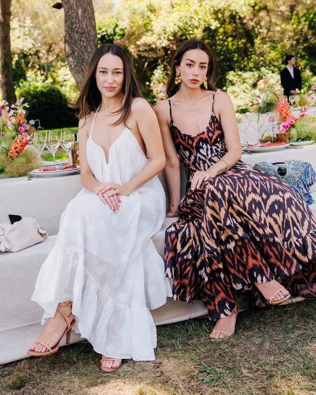 Alycia Debnam-Carey sitting with a companion outdoors in a white dress.