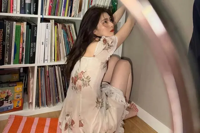 Han So-hee sitting barefoot beside bookshelves.