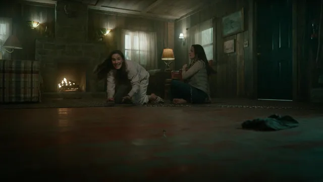 Elizabeth Gillies sitting with a companion during a screen scene.