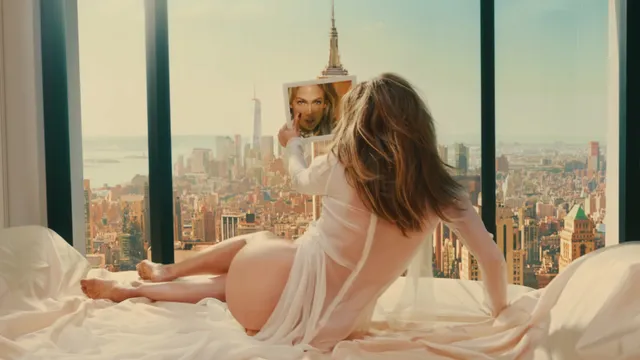 Jennifer Lopez a pale outfit while relaxing beside a city window.