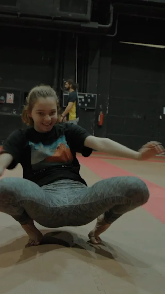 Emma Myers balancing barefoot on a gym floor during training.